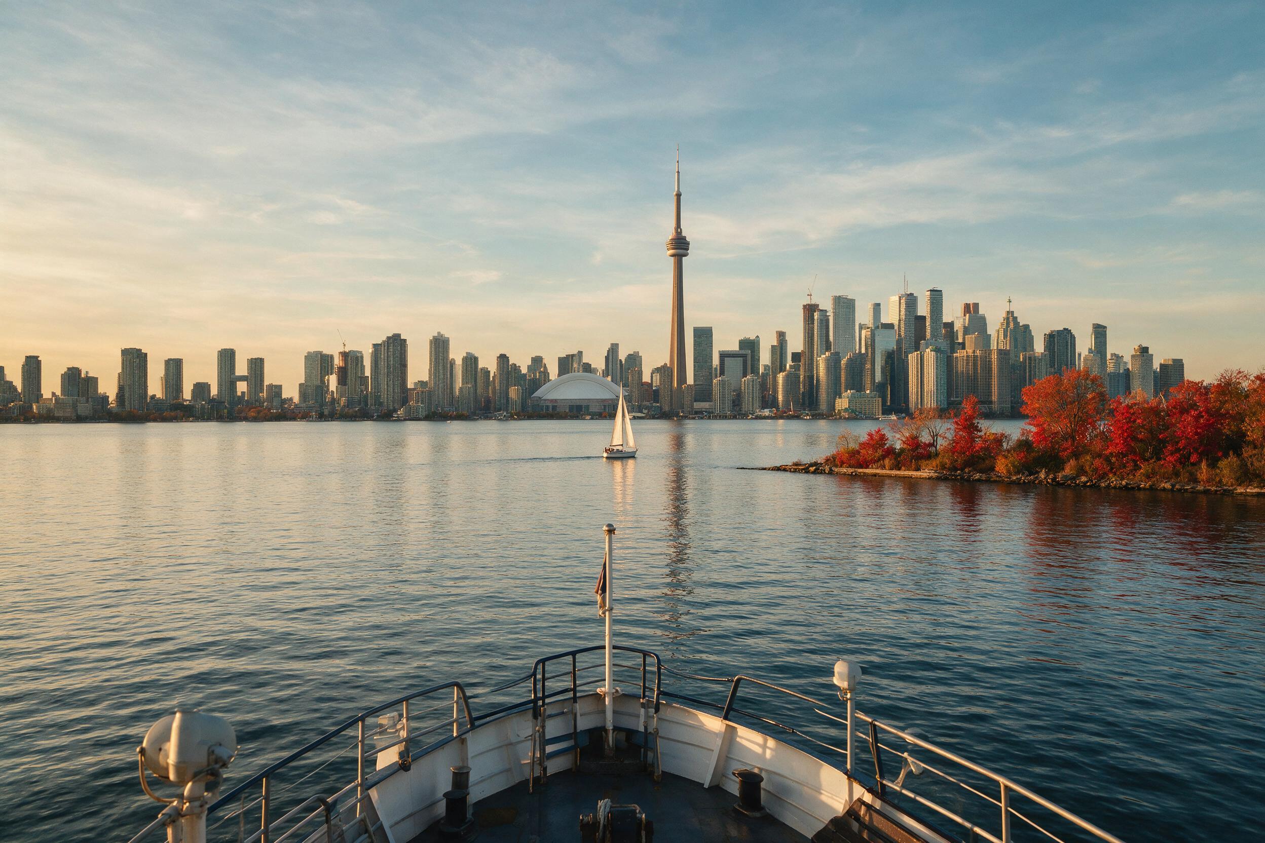 Toronto skyline and CN Tower seen from Toronto Island ferry with autumn foliage in the foreground
