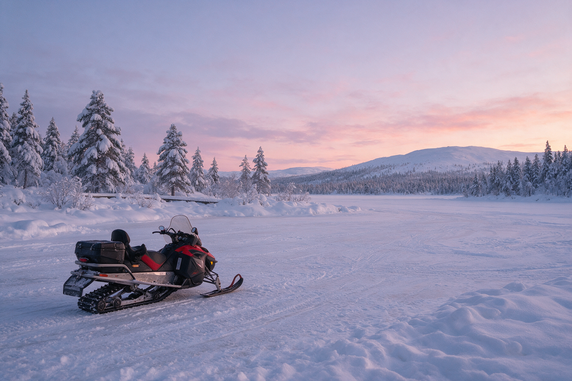 Frozen lake near Inari at dusk with a snowmobile on the ice
