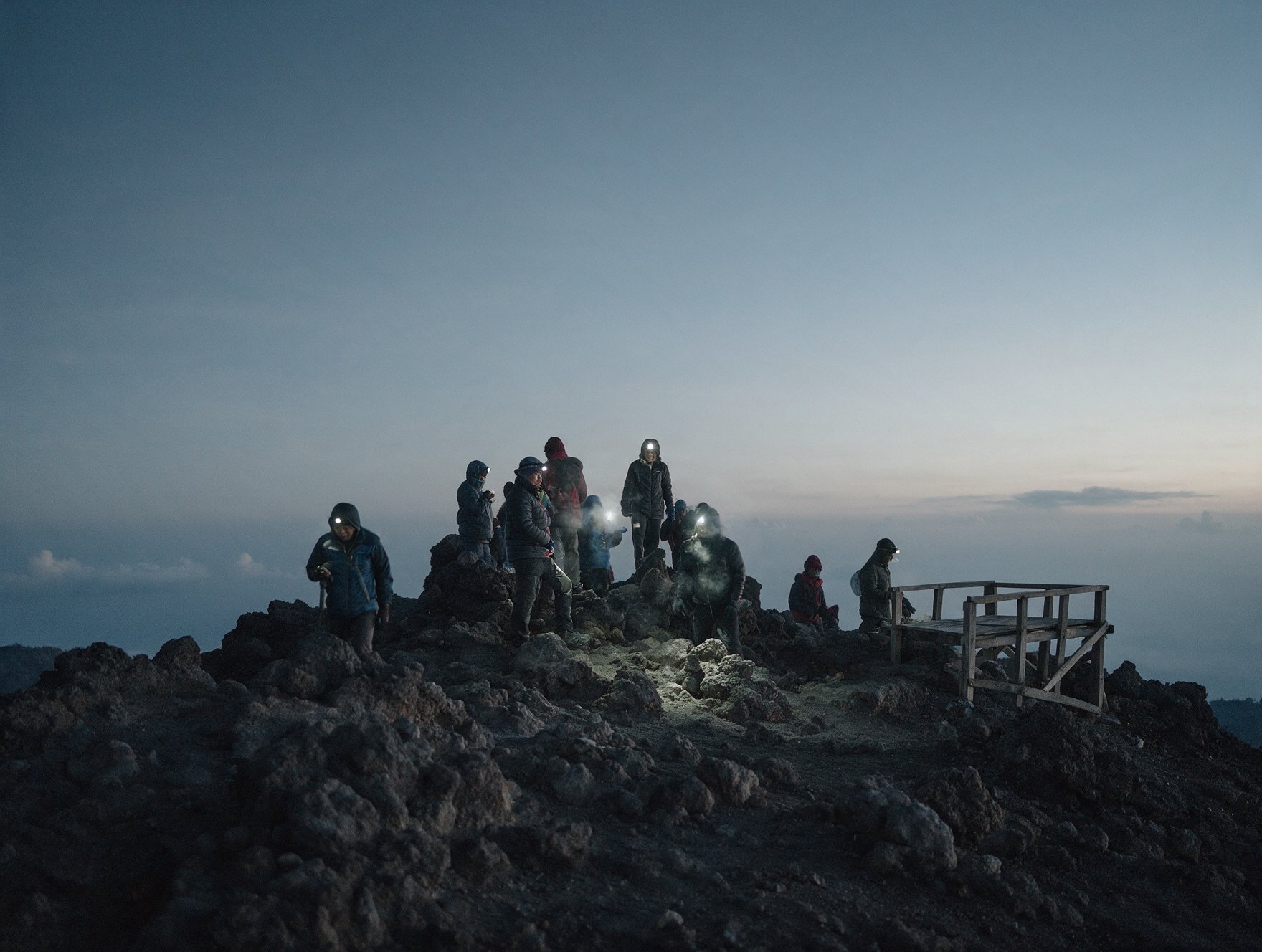 Hikers in warm jackets at the summit of Mount Batur before sunrise