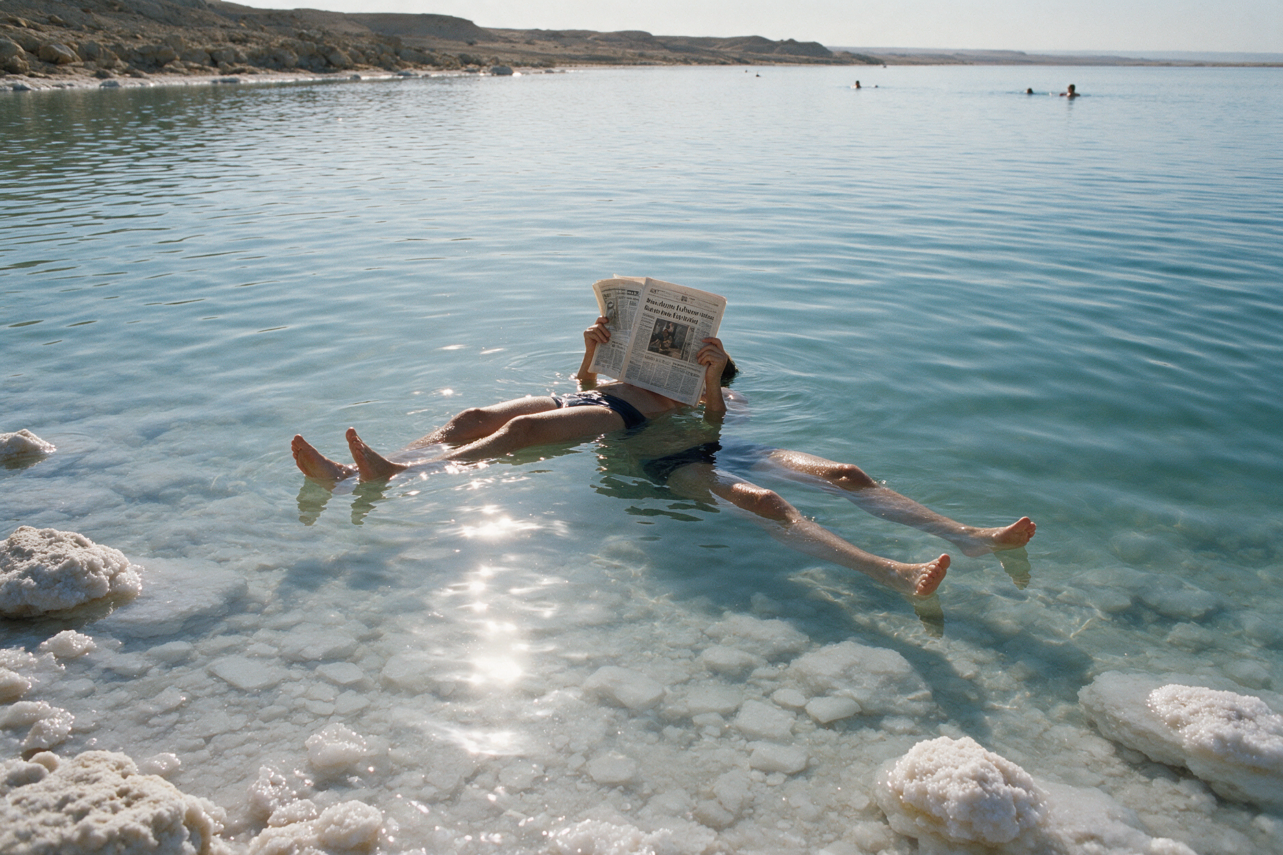 A traveler floating on their back in the calm salty water of the Dead Sea near the Jordanian shore