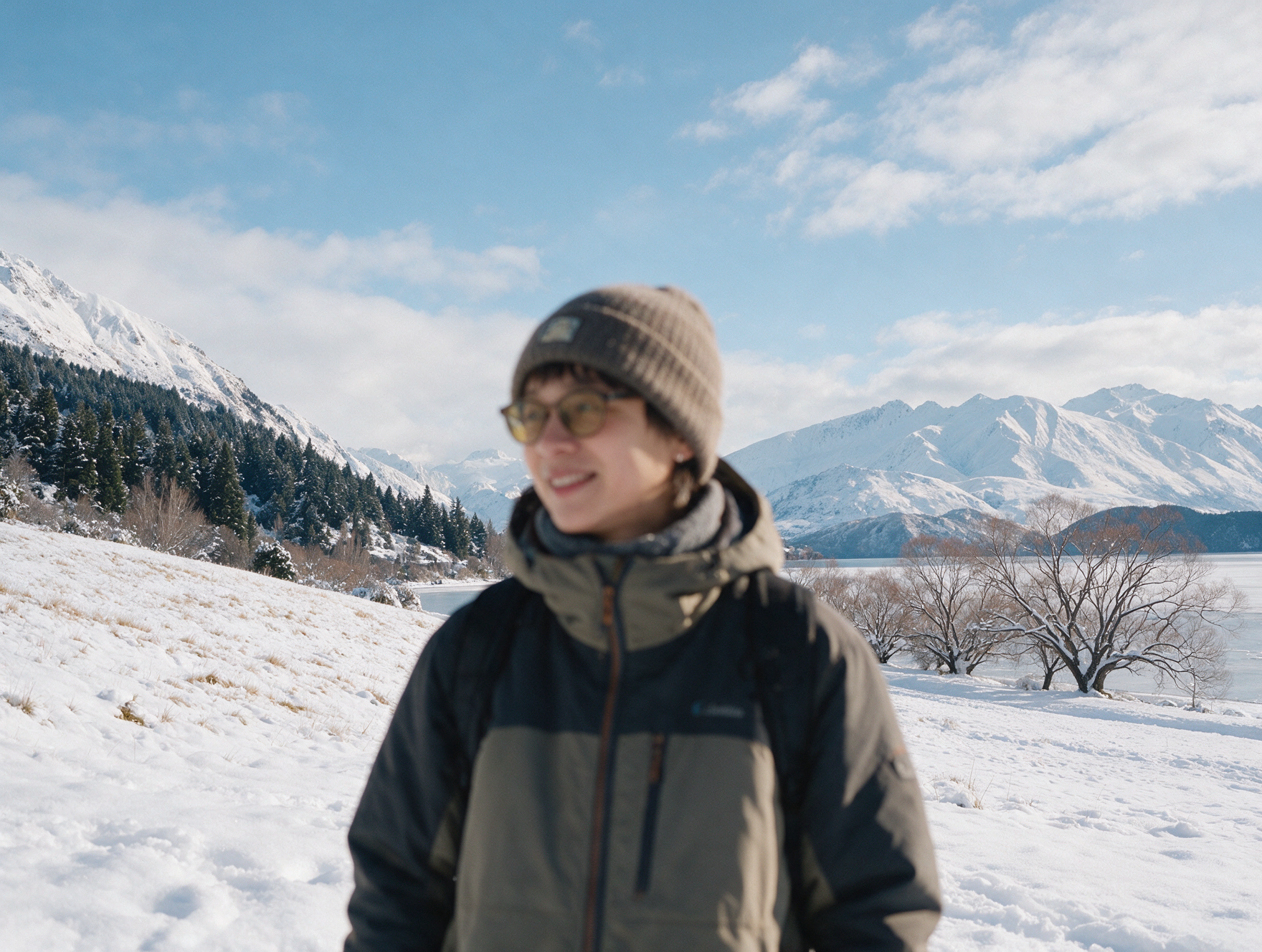 Traveler in a warm insulated winter jacket and beanie standing in snow near Queenstown New Zealand mountains